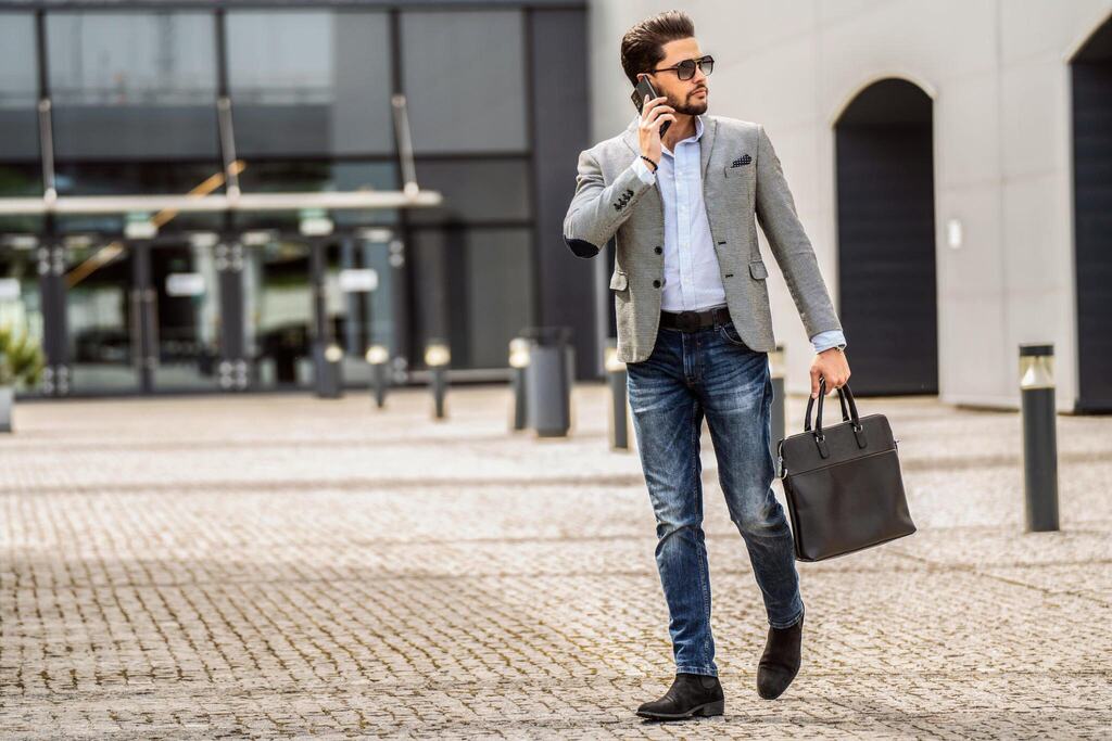 Handsome man walking on the street, talking via mobile phone.